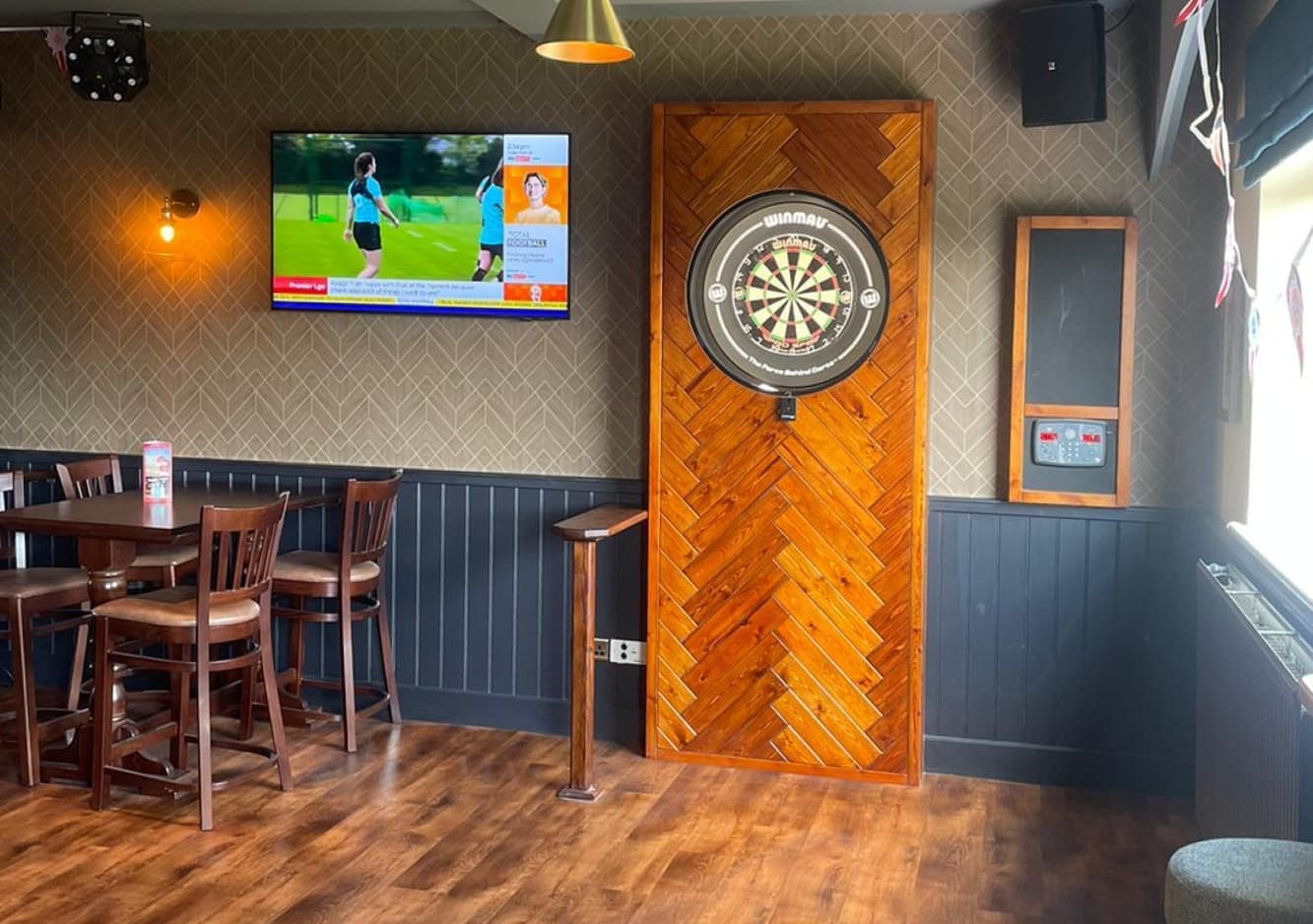 Dart board and HD screens showing the sports facilities of the pub