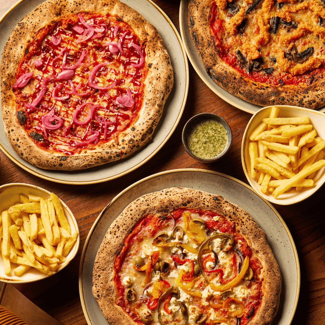 3 pizzas and sides on table