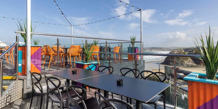 Chairs and tables on decking next to the sea
