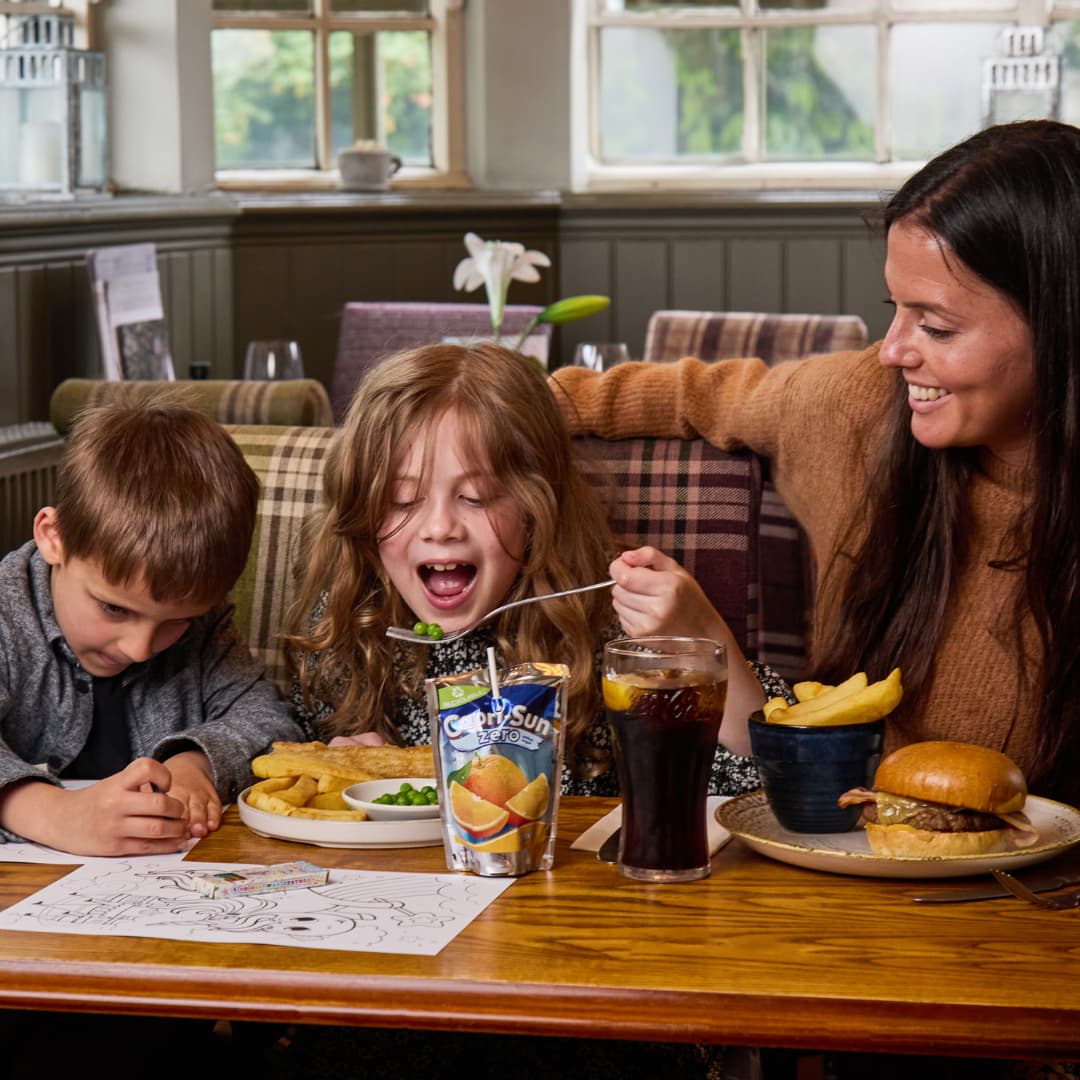 two children and a parent enjoying a meal in a pub