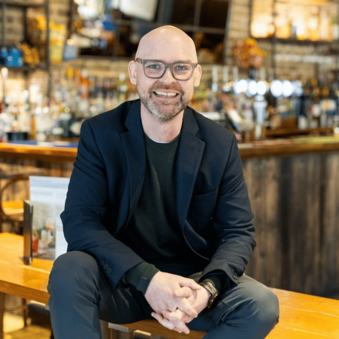 Image of David McDowall, CEO of Stonegate Group sat on a table
