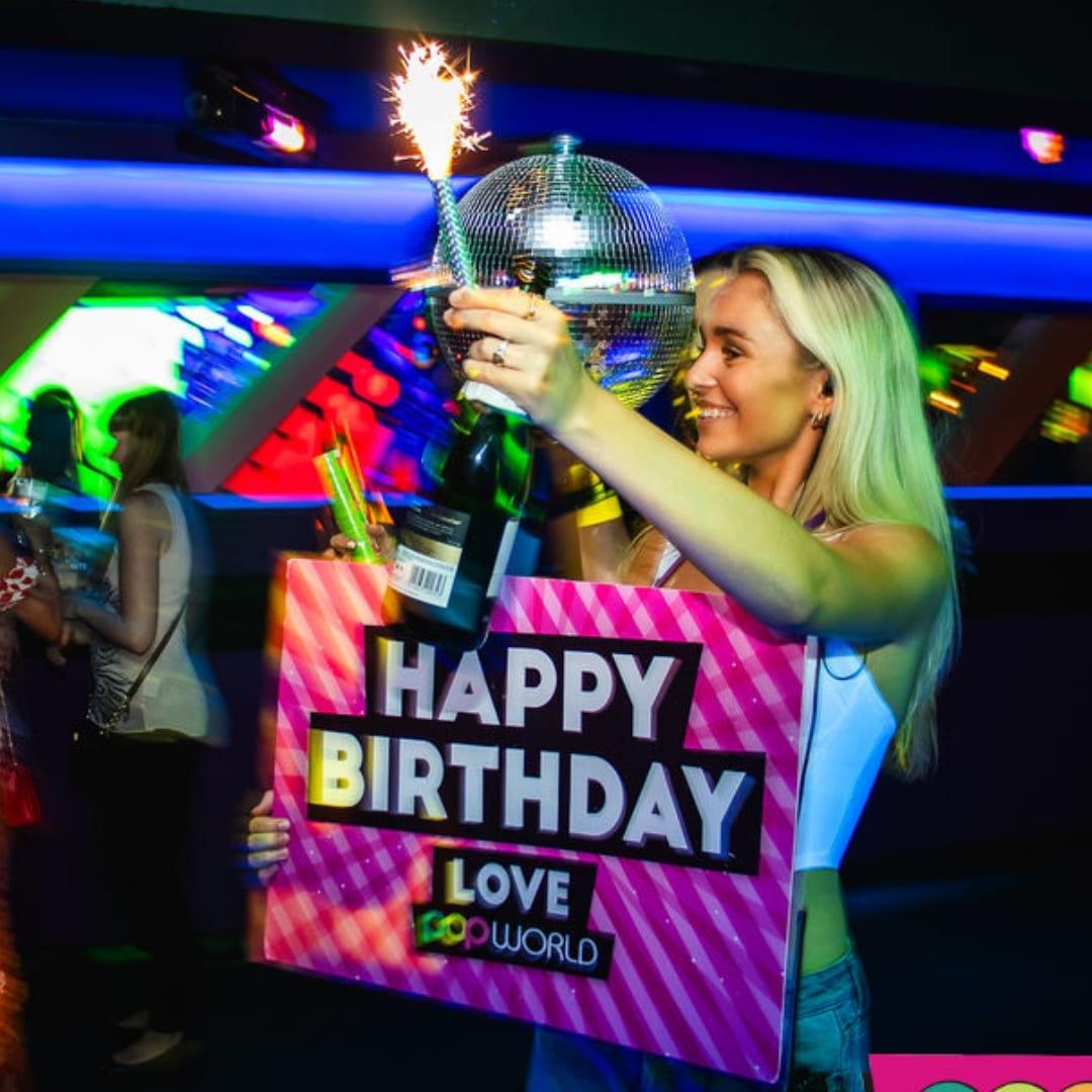 Popworld team member holding a sparkler and sign that says 'Happy Birthday'