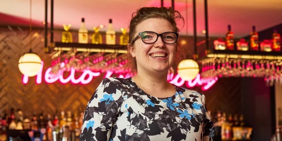 General Manager smiling in front of bar.