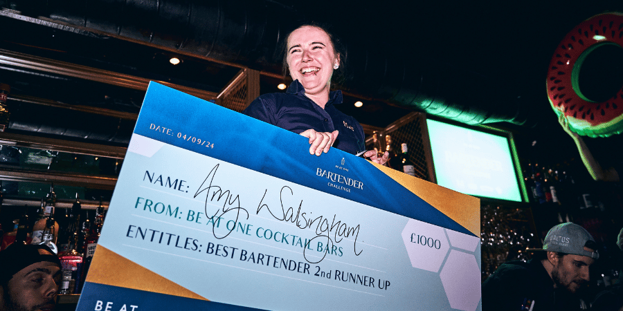 Amy, second runner up celebrating with friends while holding a cheque