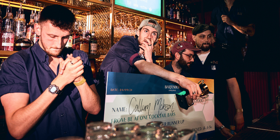 Callum, 2nd place Best Bartender holding a cheque behind the bar