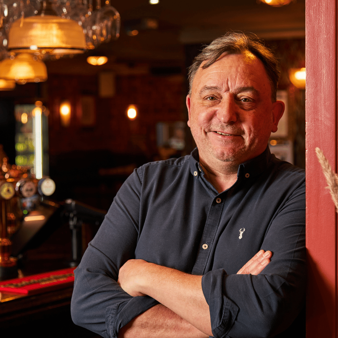 Pubsmiths General Manager smiling at the camera, arms crossed and leaning on a wall.