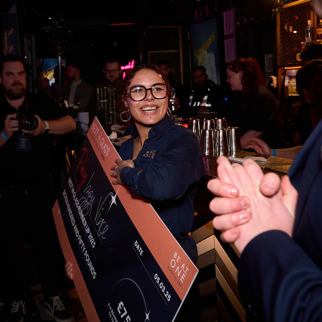 Be At One Bartender holding a large cheque.