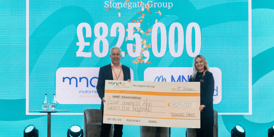Image of Tim Painter, HR Director presenting a representative of MNDA with a cheque.