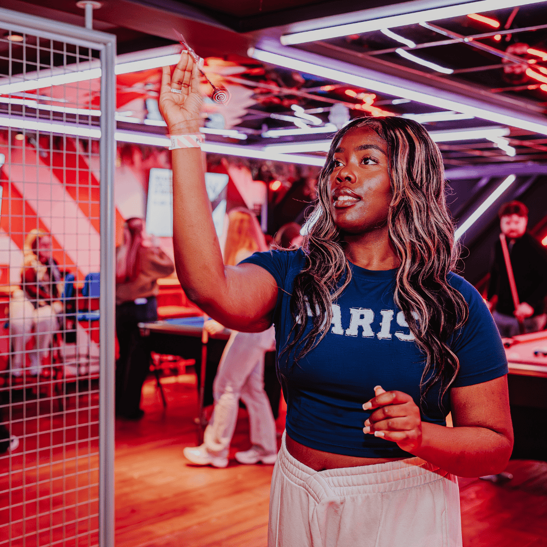 A guest playing darts at PLAYBOX in Croydon