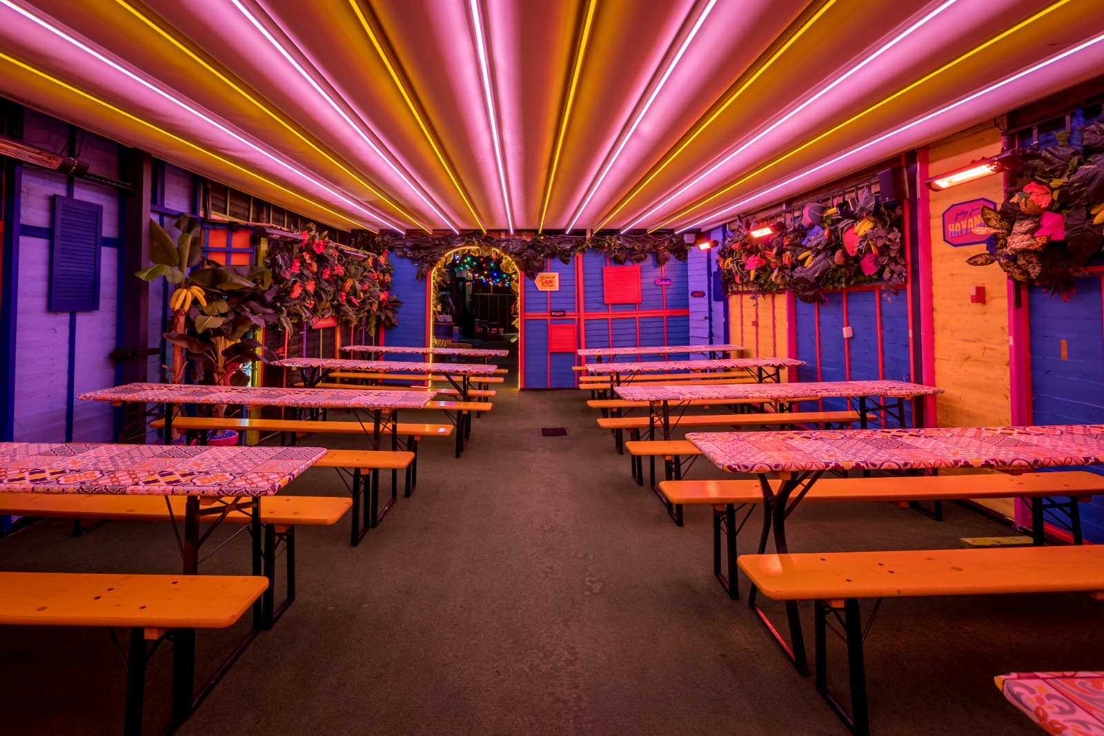 A covered outdoor seating area with neon lights across the ceiling. 