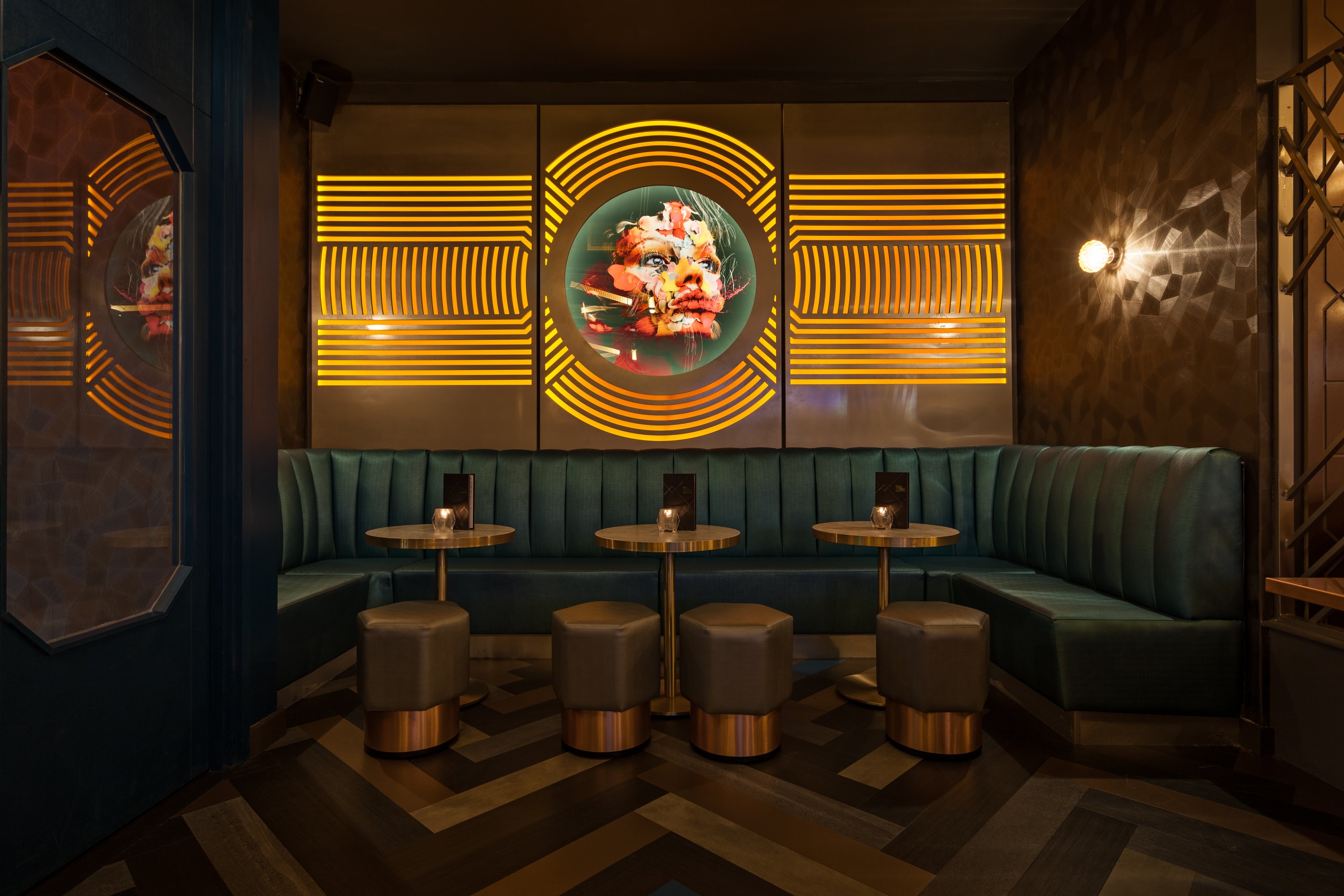 A booth seating area with light up artwork on the wall in Dirty Martini Manchester