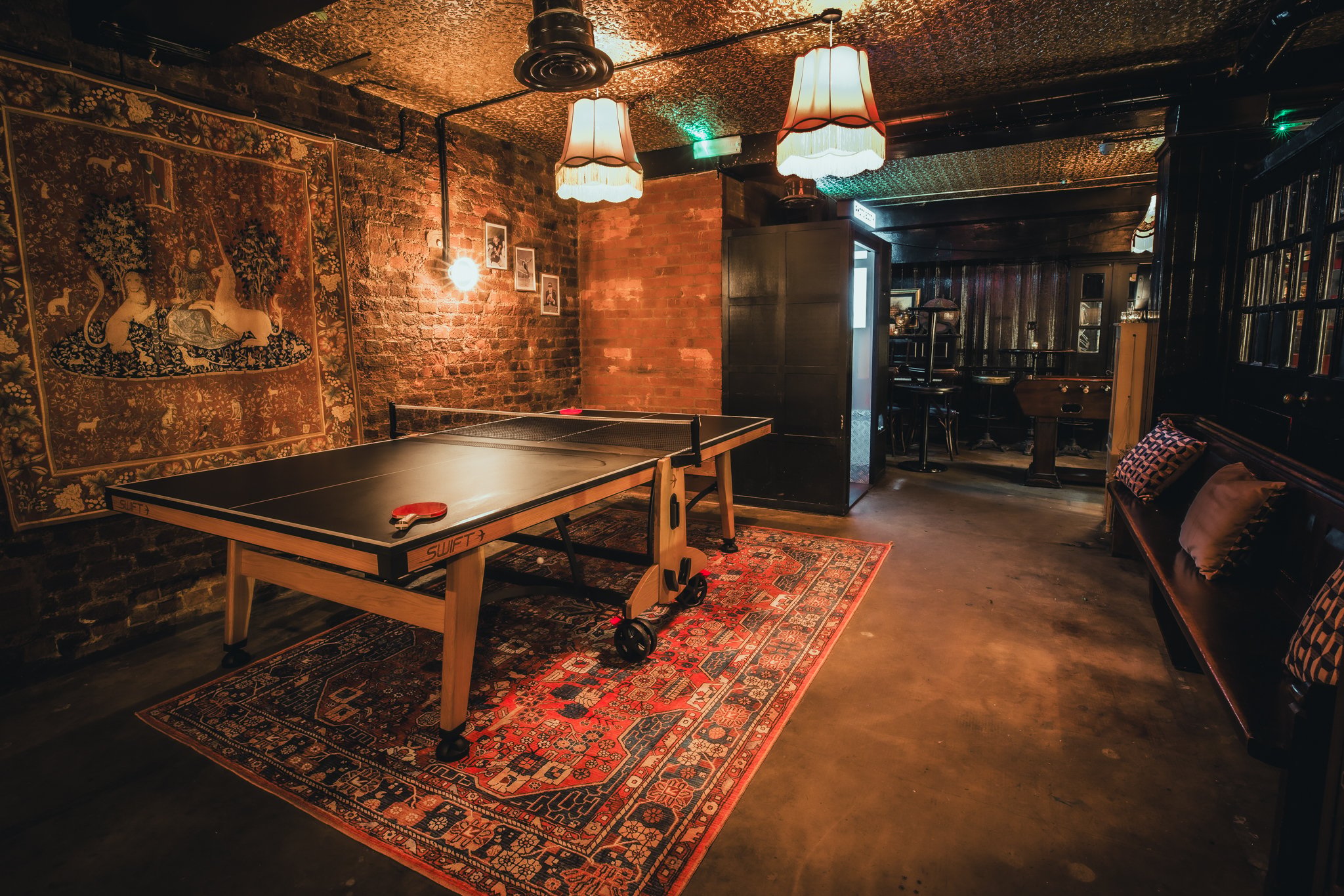 A private area of a bar with exposed brick walls and a ping pong table