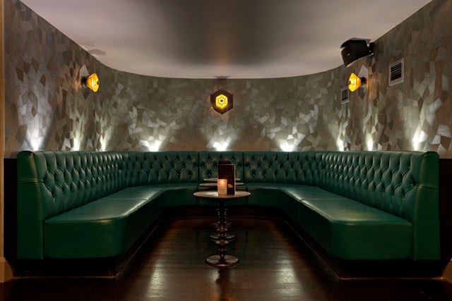 A private seating area in a bar with green booth seating