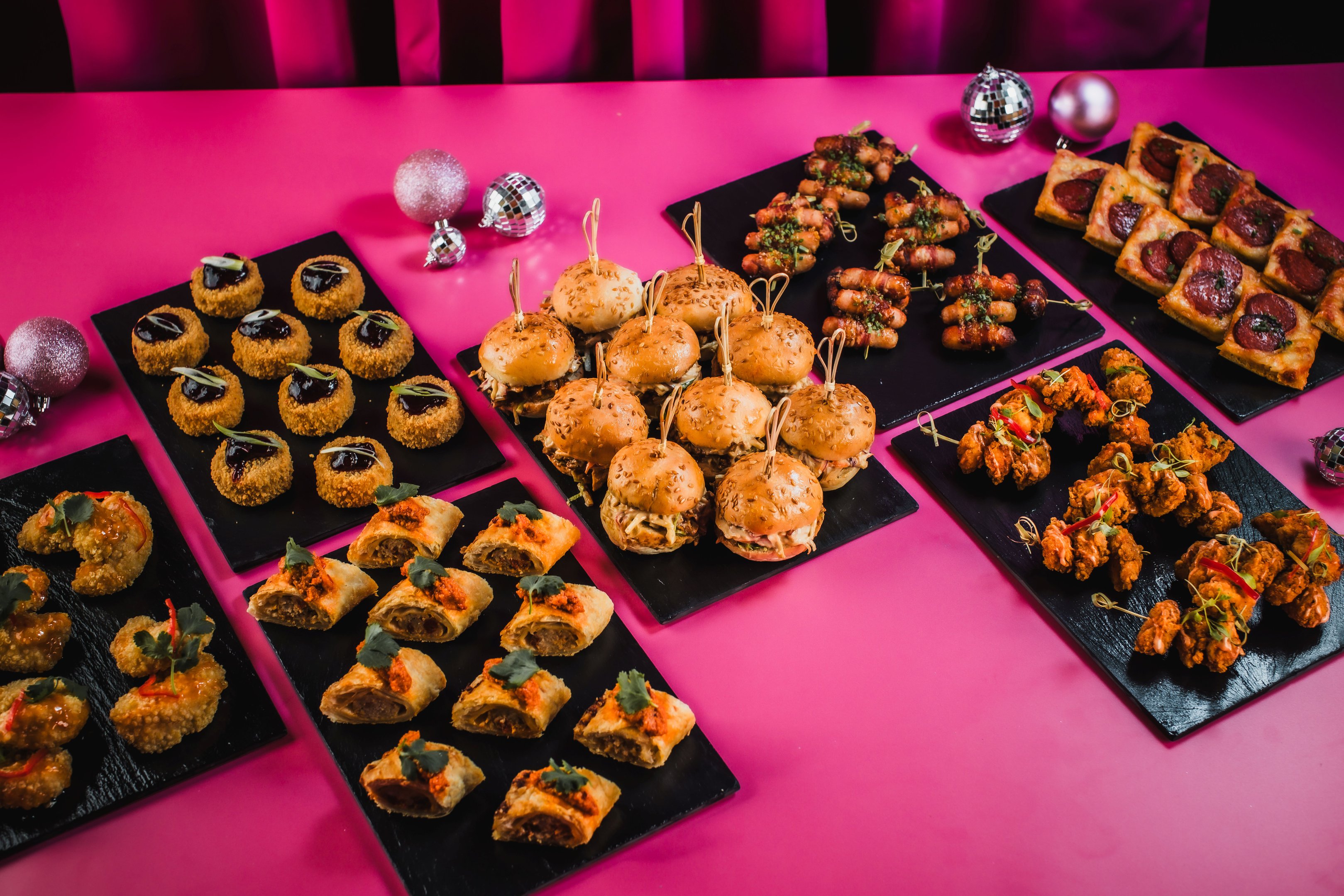 Platters of Christmas finger food on a pink tabletop at Tonight Josephine
