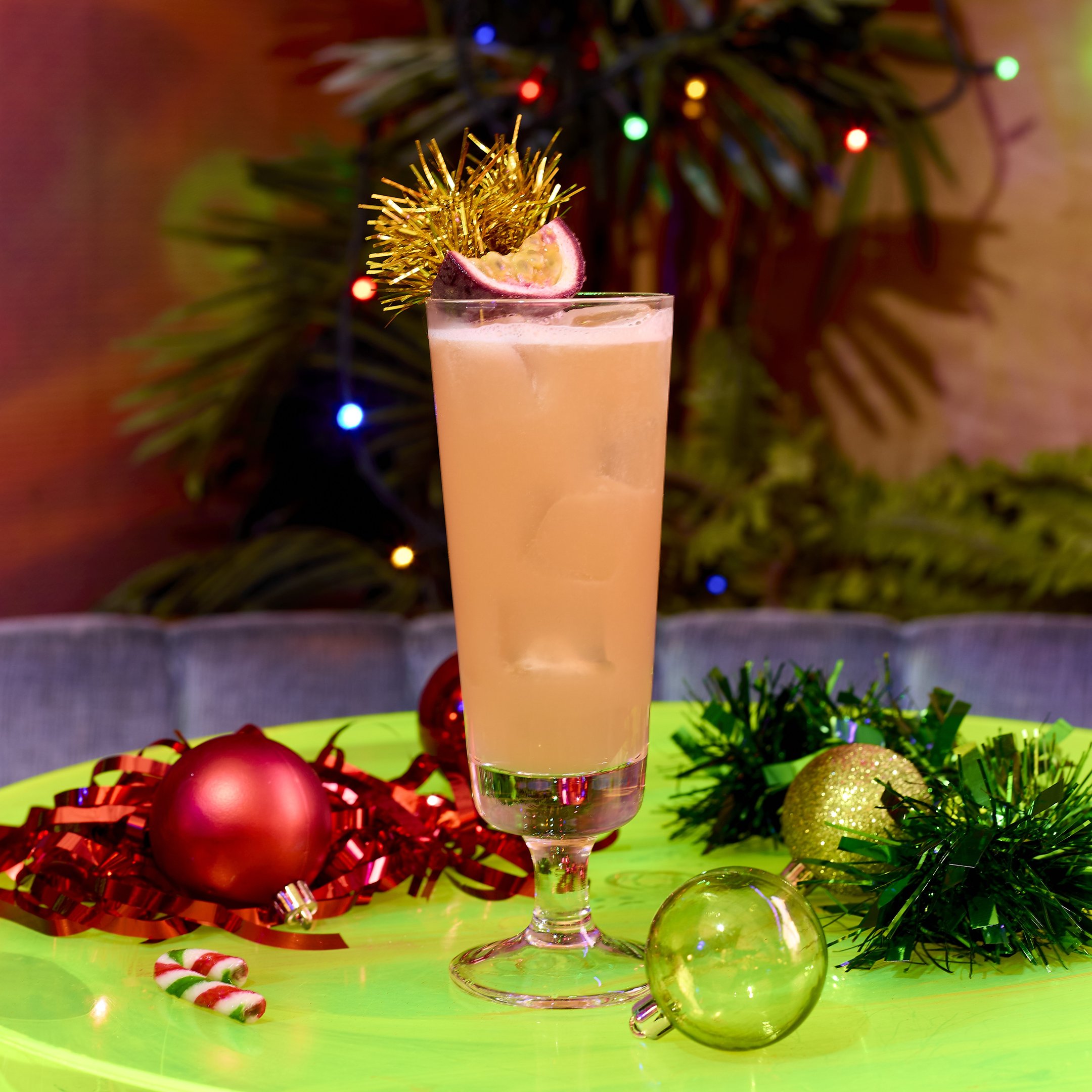 Cocktail in a tall glass with a grapefruit and tinsel garnish