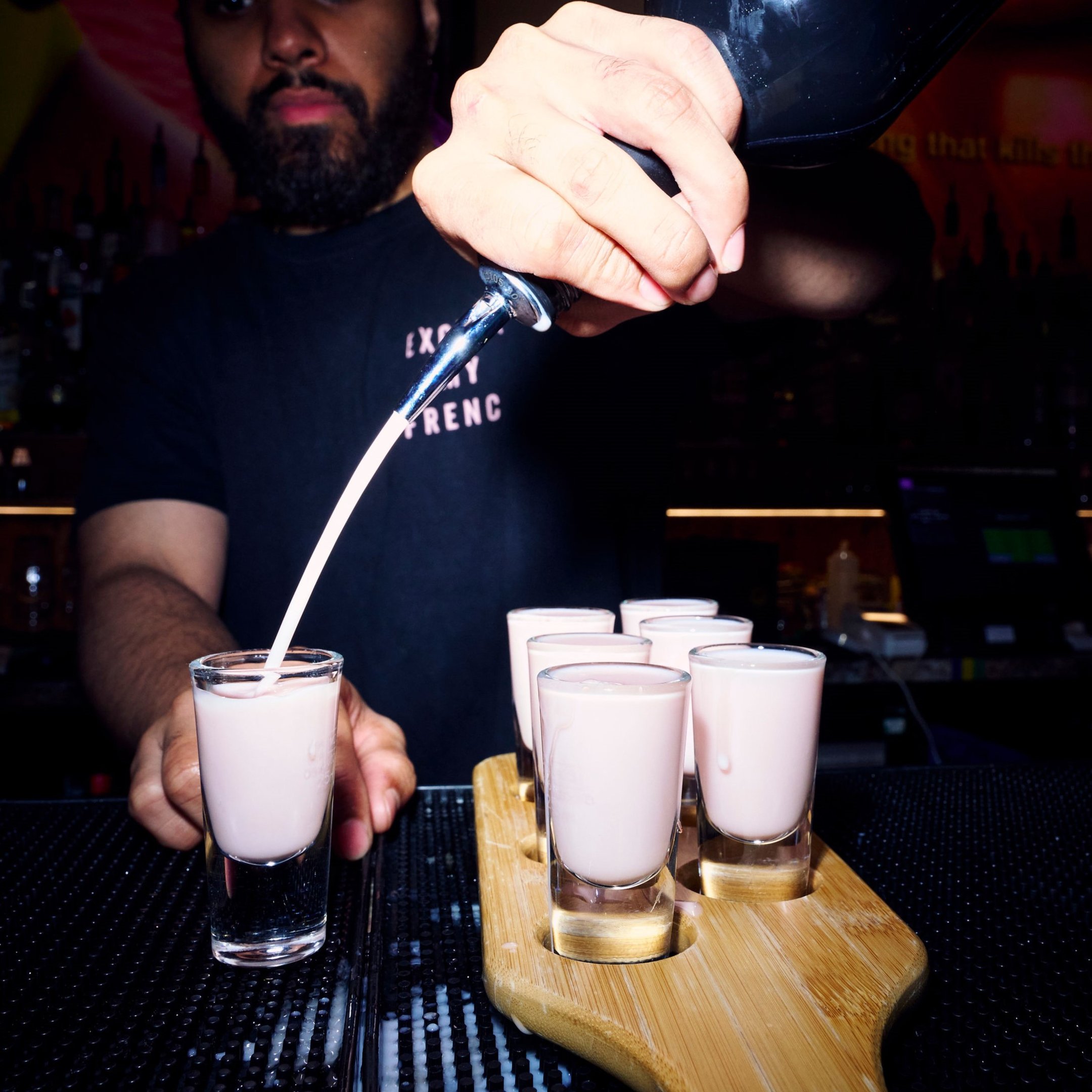 A bartender pouring shots of Tequila Rose for a shot paddle in Nikki's bar