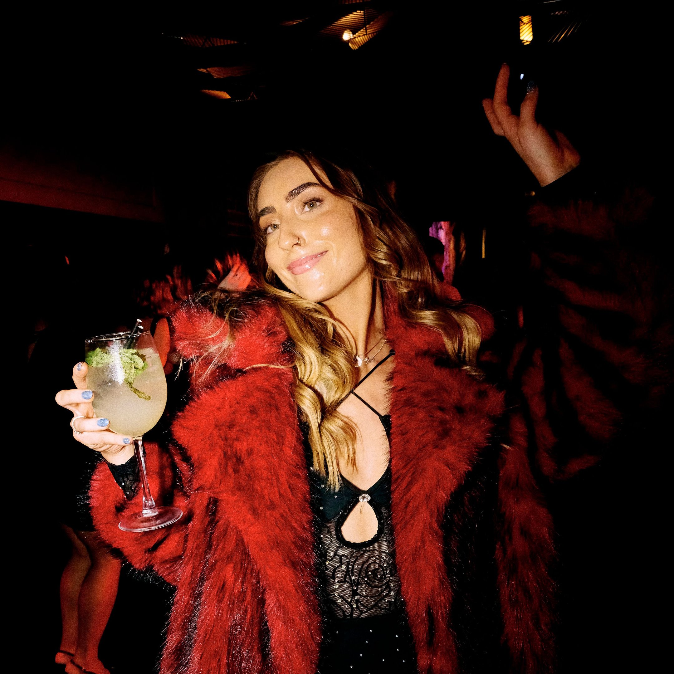 A woman drinking a cocktail and dancing in Dirty Martini