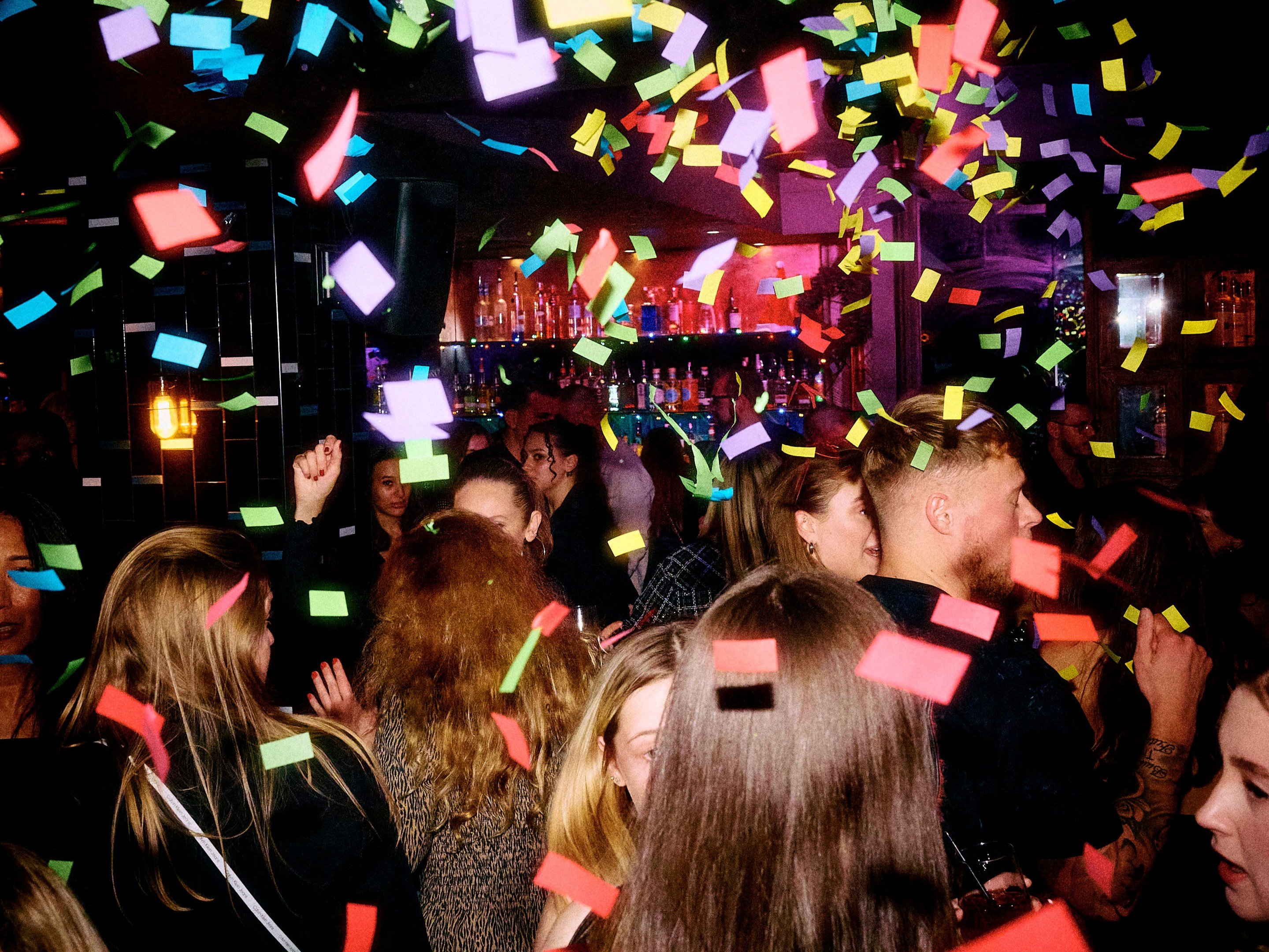 A packed dance floor with falling confetti in Dirty Martini