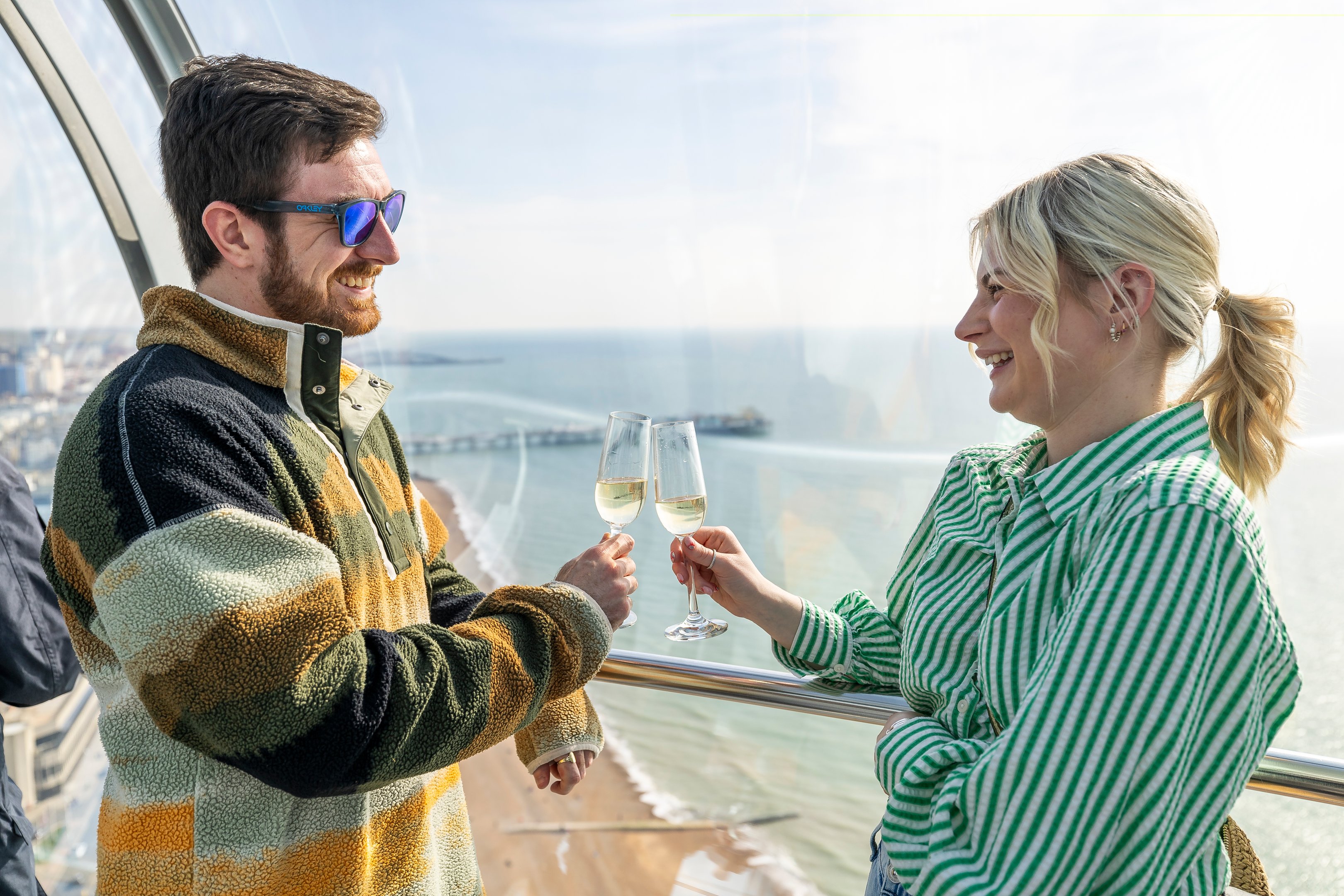 Two guests enjoying champagne looking out over Brighton in the pod on the Brighton i360