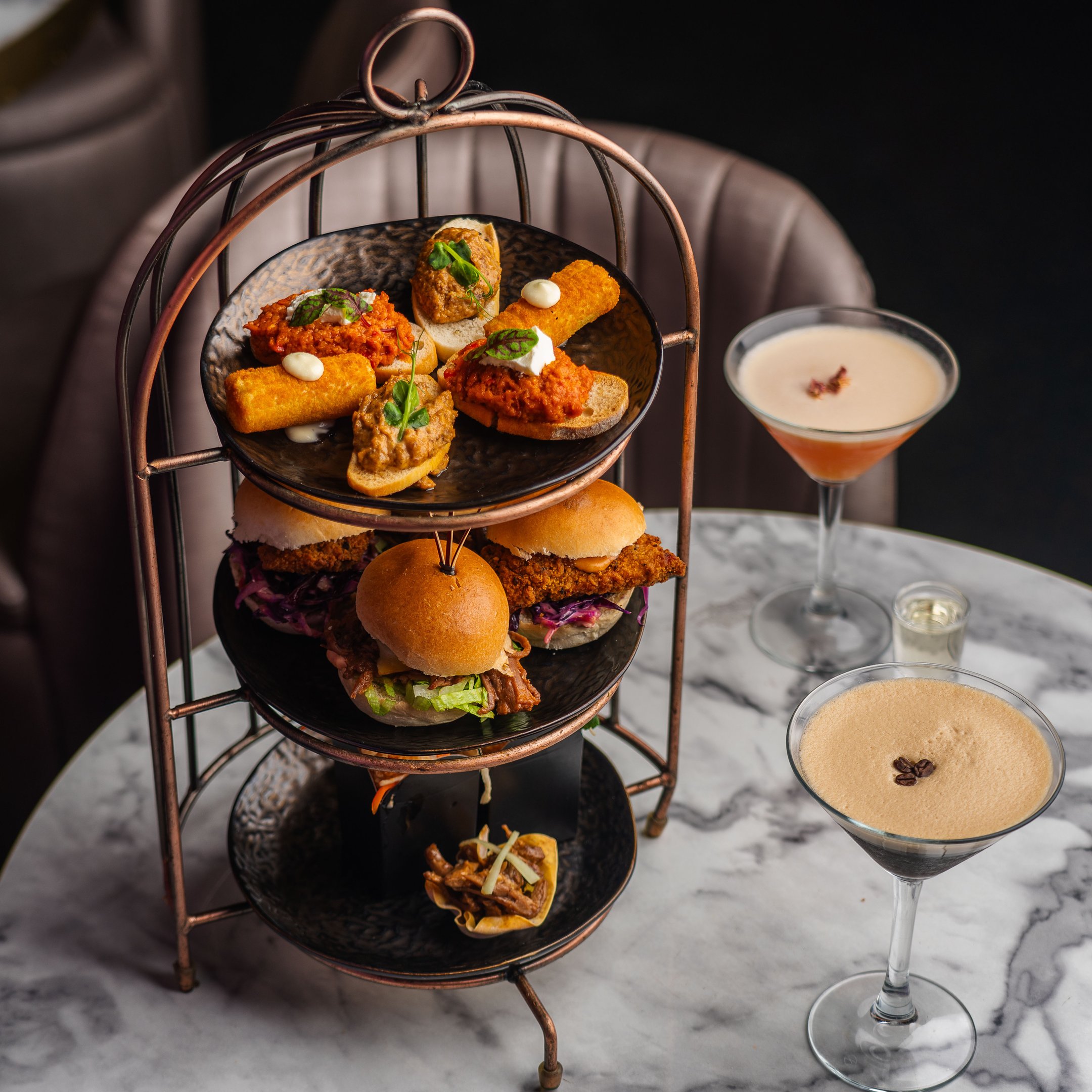 A food Birdcage sharer on a table with two cocktails in Dirty Martini