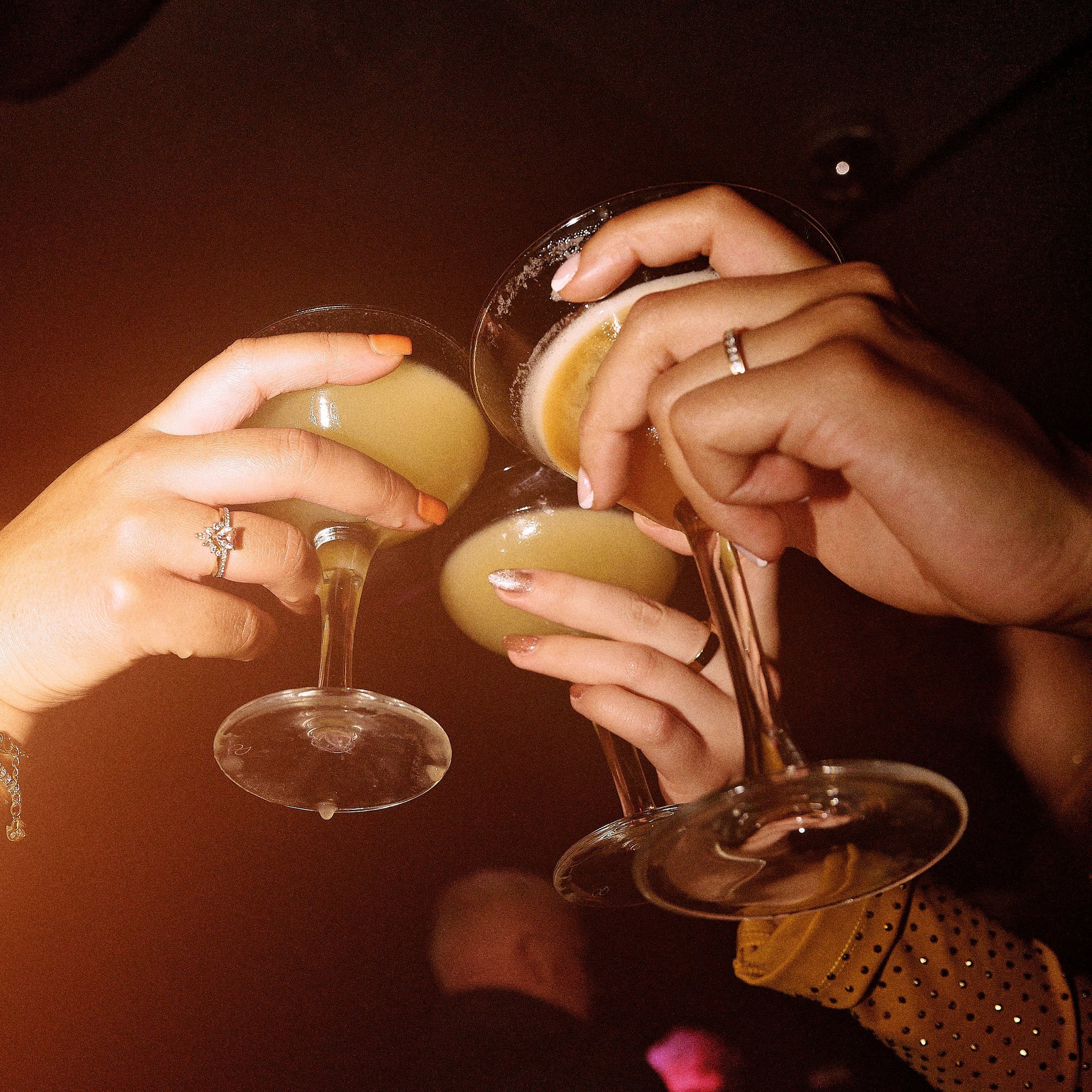 Guests holding cocktails in the air in Dirty Martini 