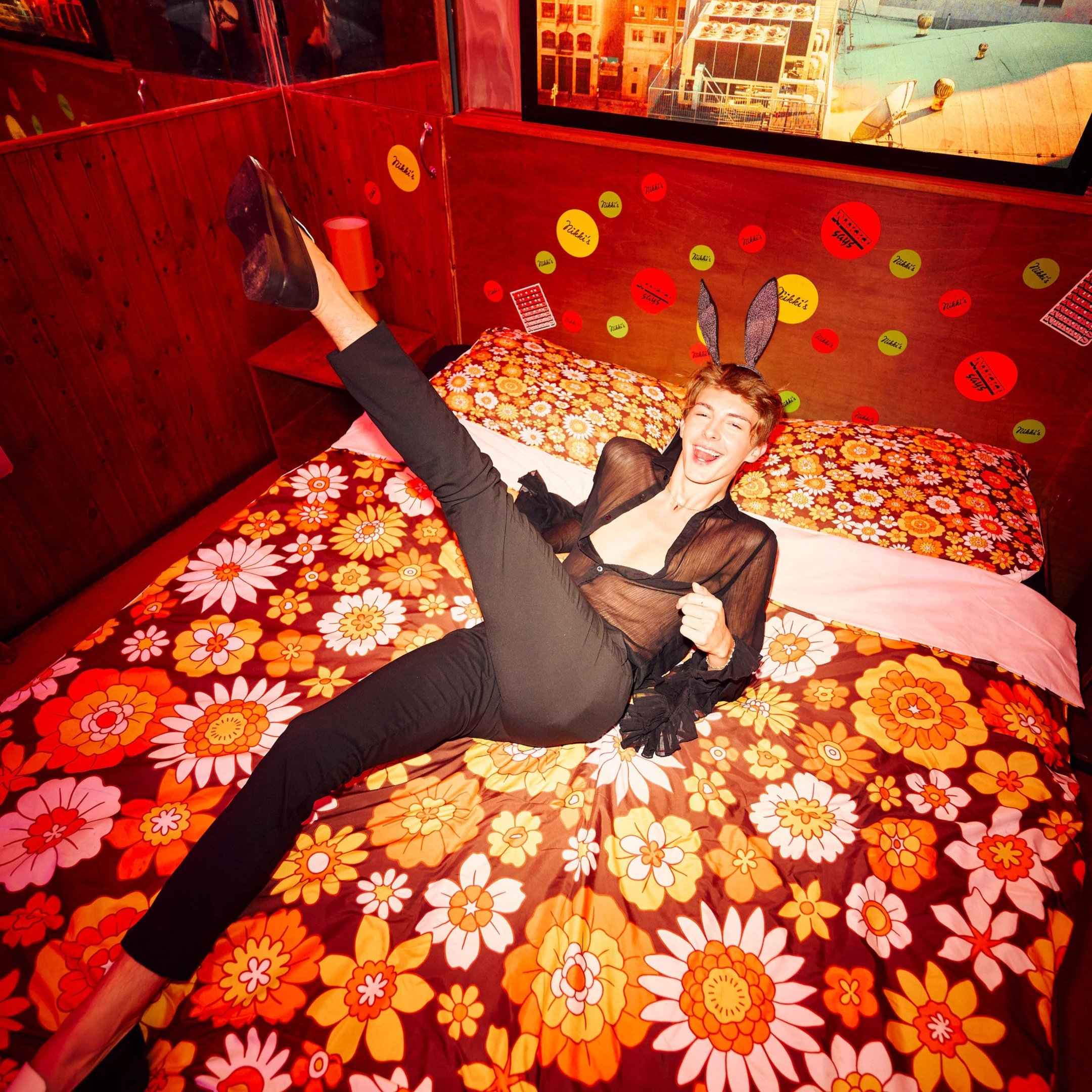 A guest posing on a bed in Nikki's bar wearing bunny ears