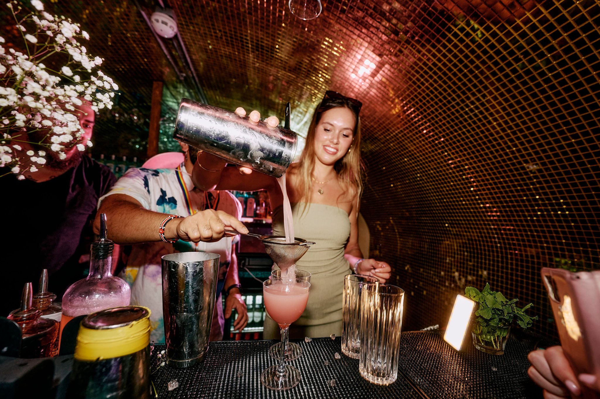 A guest in Blame Gloria pouring a cocktail behind the bar