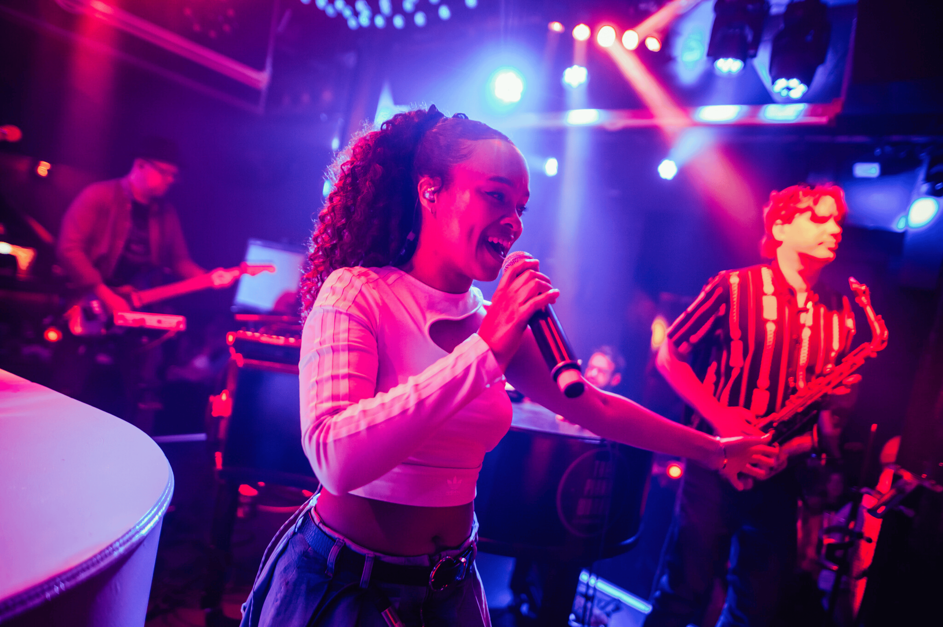 A female singer with a full band performing on a stage in The Piano Works