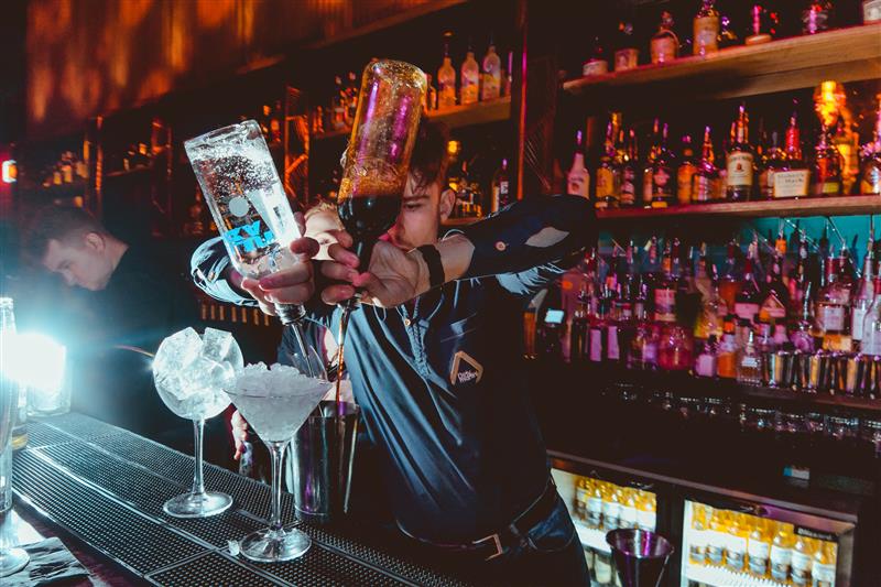 A bartender pouring cocktails on the bar in Dirty Martini