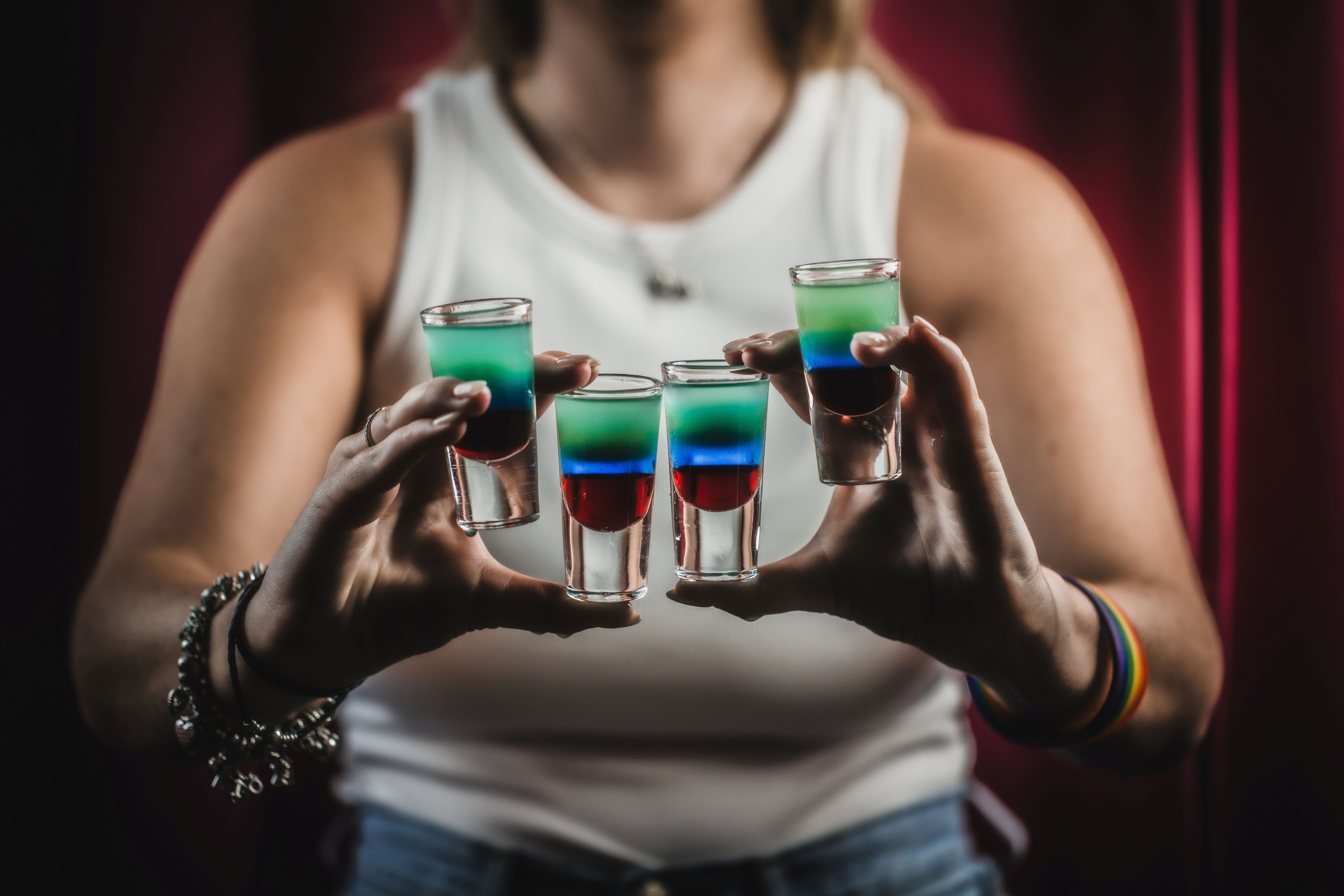 A person holding 4 special pride shots in their hands