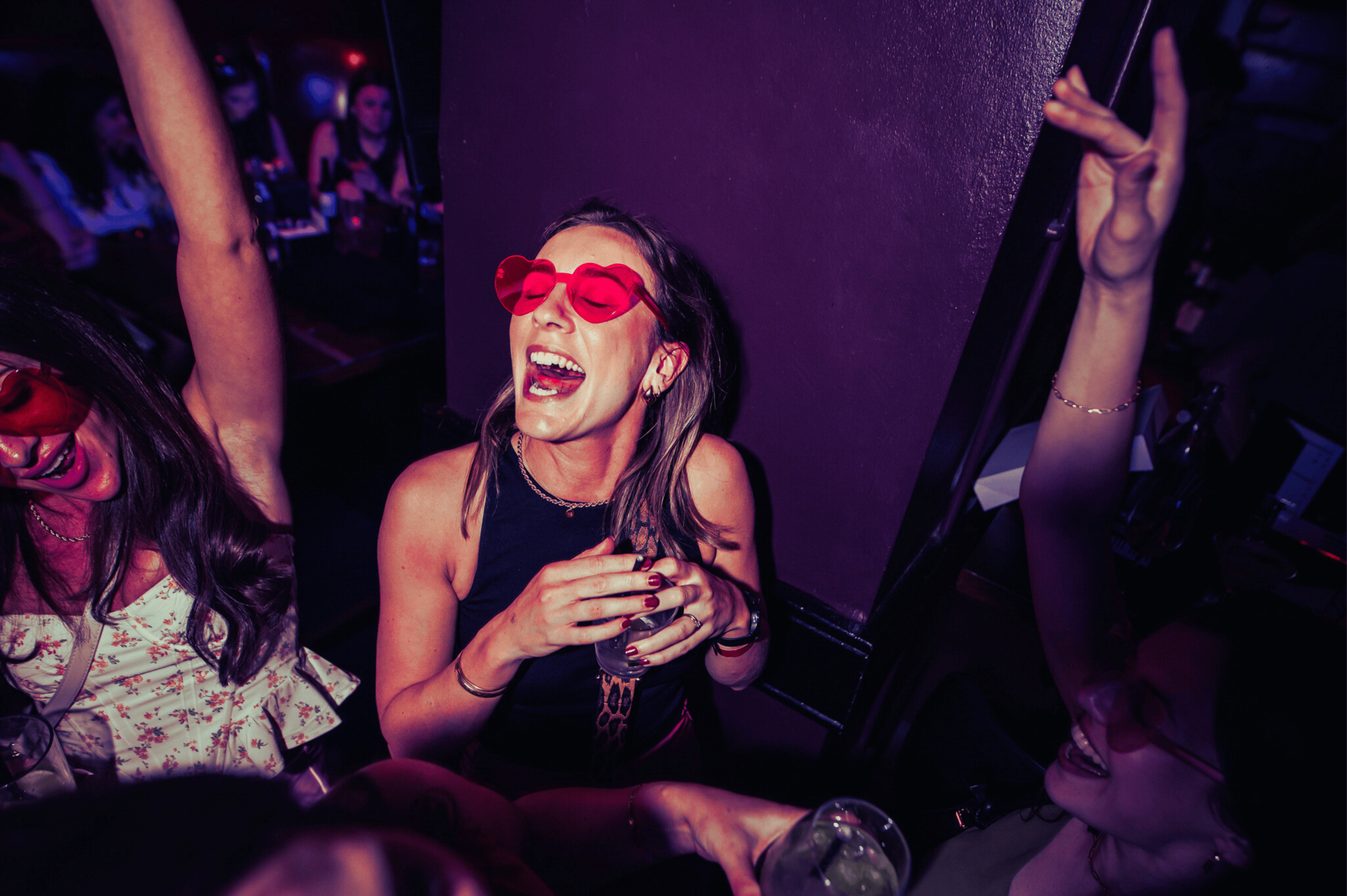 A guest wearing red heart glasses singing and dancing in The Piano Works