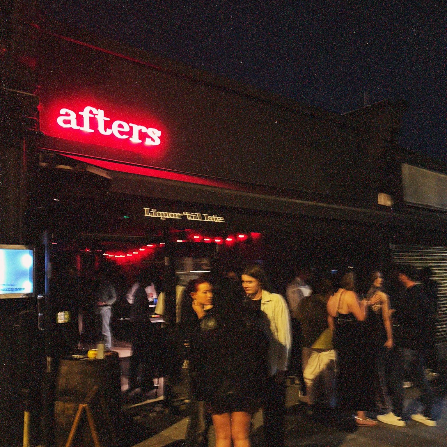 Afters bar with a neon Afters sign and customers standing outside