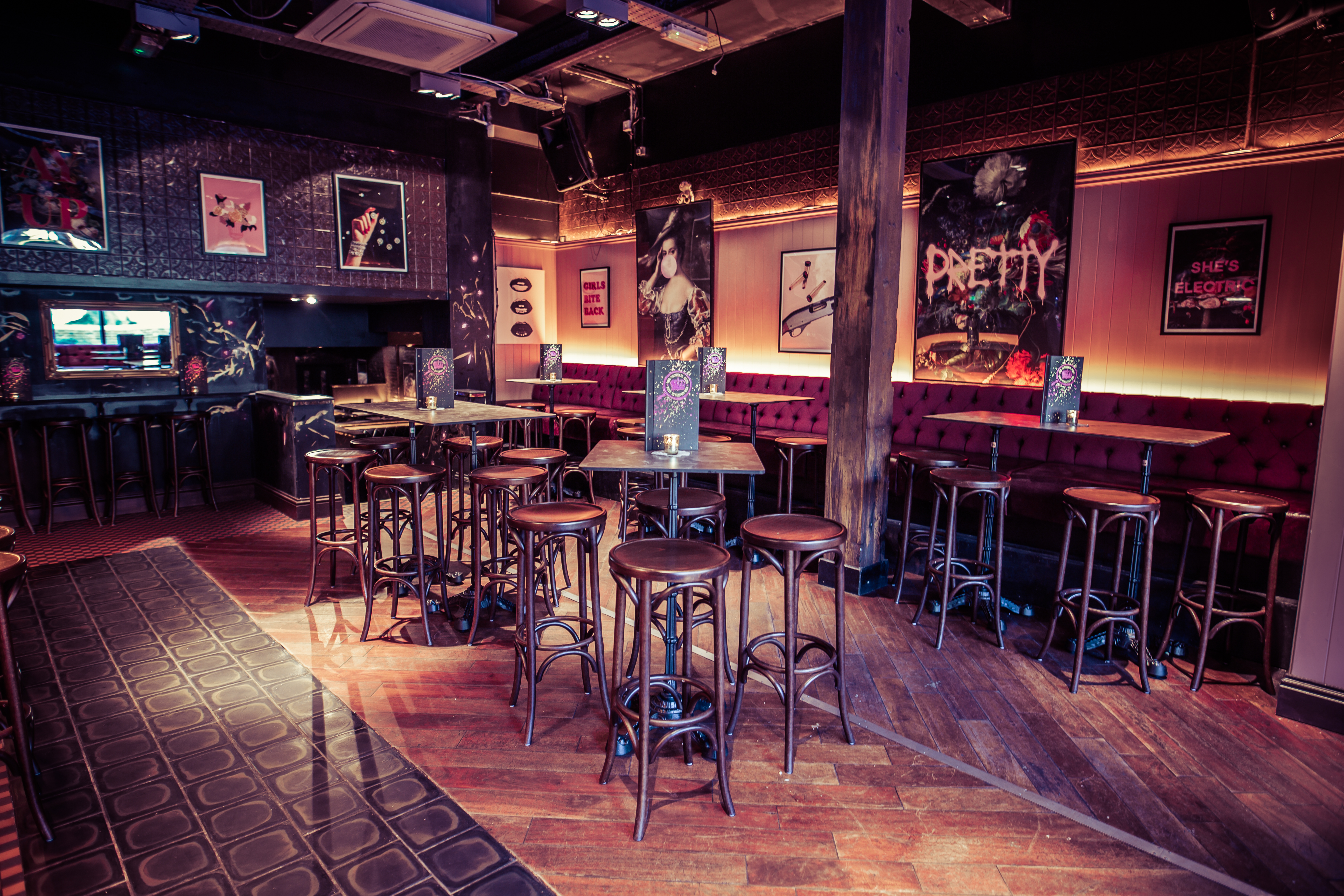 A bar area with high stool seating and tables and bold artwork on the walls