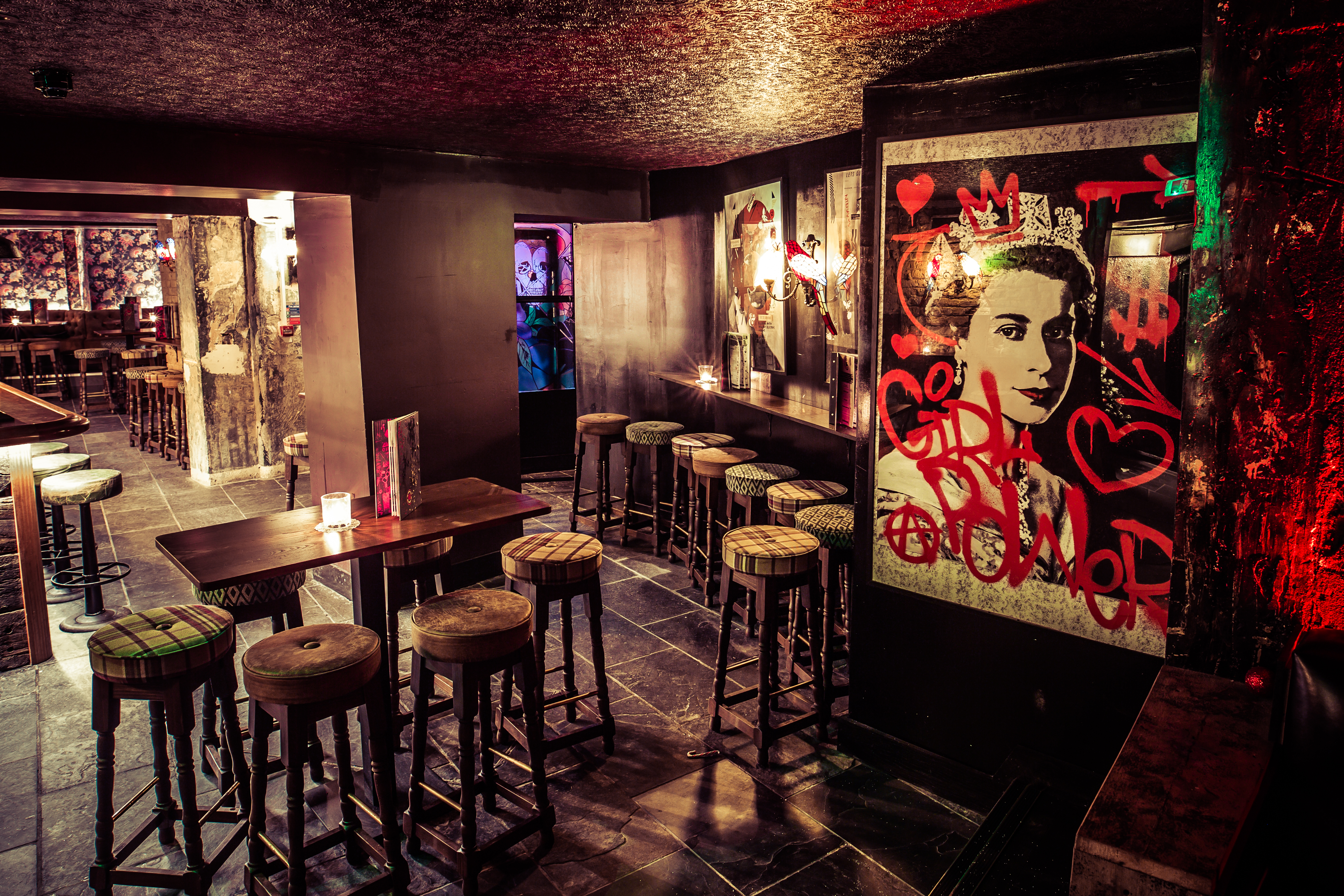 Bar area with high tables and stool seating with graffiti art work on the walls